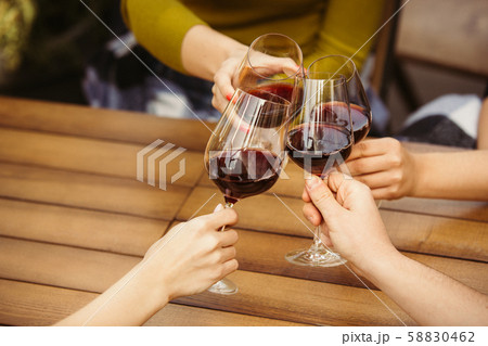 People clinking glasses with wine on the summer terrace of cafe or restaurant. Close up shot 58830462