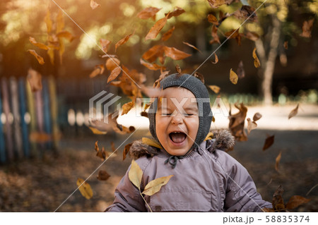 Little toddler boy in autumn park with leaves falling. Emotions of happiness and joy Little toddler boy in autumn park with leaves falling. Emotions of happiness and joy 58835374