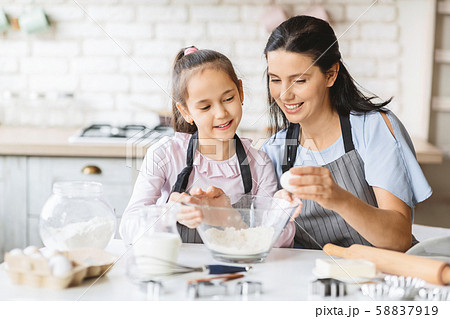 Little girl and her beautiful mother having fun cooking together 58837919