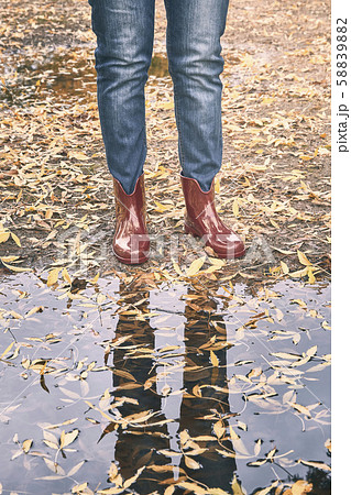 red rubber boots in front of a puddle with yellow leaf in autumn. rain concept 58839882