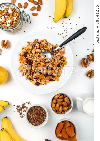 Granola muesli breakfast with with milk, dried apricots, cranberries, almonds and flax seeds in bowl 58841255