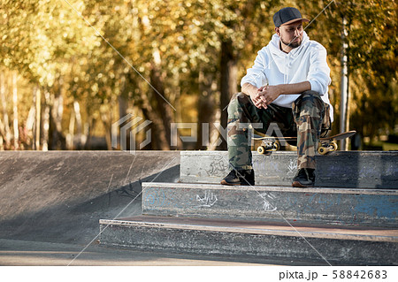 Man in skatepark with skateboard on warm autumn day Man in skatepark with skateboard on warm autumn day 58842683