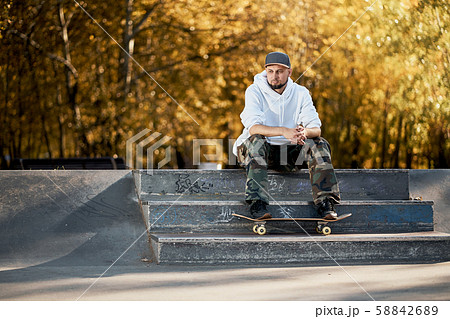Man in skatepark with skateboard on warm autumn day 58842689