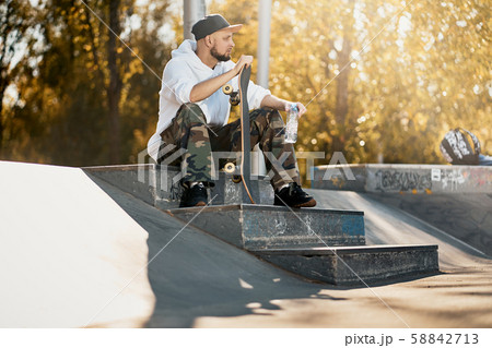 Man in skatepark with skateboard on warm autumn day 58842713