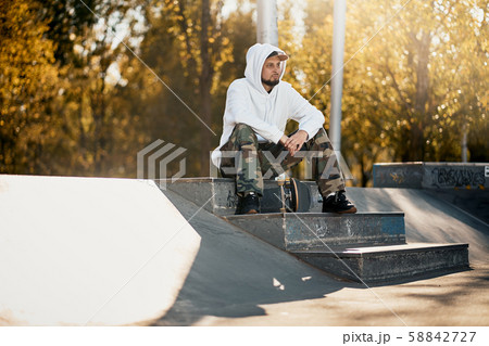 Man in skatepark with skateboard on warm autumn day 58842727