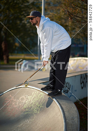 Man in skatepark rides skateboard on warm autumn day Man in skatepark rides skateboard on warm autumn day 58842729
