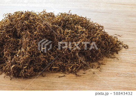 Heap of pipe tobacco on a brown wooden background. Heap of pipe tobacco on a brown wooden background. 58843432
