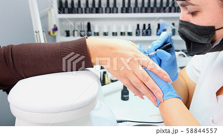 Manicurist paints nails to a client in a beauty salon. Gel polish. Lacquer. Manicure. Nail extension Manicurist paints nails to a client in a beauty salon. Gel polish. Lacquer. Manicure. Nail extension 58844557