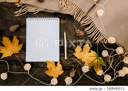 White blank notebook and pen on a dark background with a scarf, plaid and a cup, autumn yellow 58846011