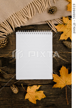 White blank notebook and pen on a dark background with a scarf, plaid and a cup, autumn yellow White blank notebook and pen on a dark background with a scarf, plaid and a cup, autumn yellow 58846019