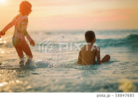 sister and brother on the beach at sunset, rear view. 58847685