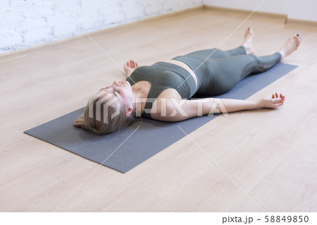 Woman laying on mat in relaxing pose on the floor. Yoga class, the shavasana. 58849850