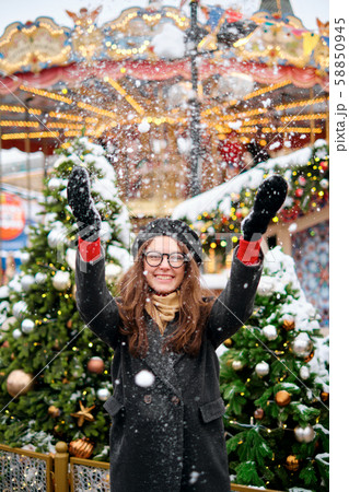 Girl playing with snow in park. young girl throws snow up, a beautiful fair with lights and bulbs Girl playing with snow in park. young girl throws snow up, a beautiful fair with lights and bulbs 58850945