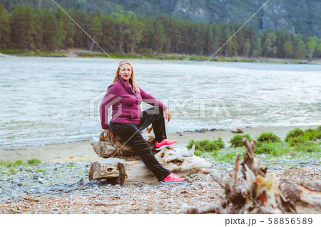 an elderly woman sitting near the river 58856589