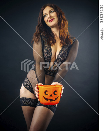Sexy woman smiling and holding Halloween pumpkin Sexy woman smiling and holding Halloween pumpkin 58857159