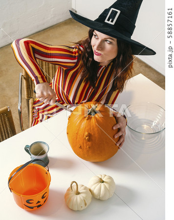 Redhead woman cutting a pumpkin for Halloween 58857161
