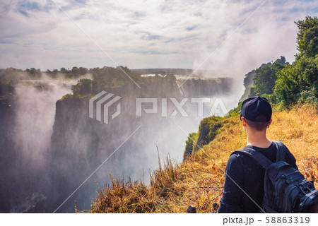 Tourist looks at the Victoria Falls on Zambezi River in Zimbabwe Tourist looks at the Victoria Falls on Zambezi River in Zimbabwe 58863319