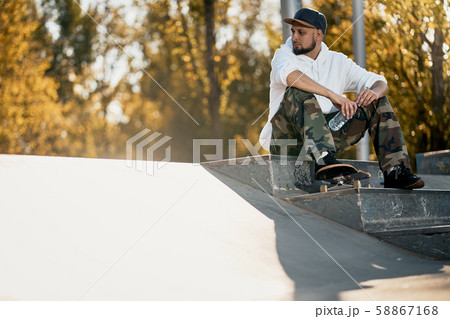 Man in skatepark with skateboard on warm autumn day Man in skatepark with skateboard on warm autumn day 58867168