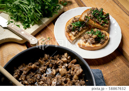 Toasts with mushrooms on white plate on wooden kitchen table Toasts with mushrooms on white plate on wooden kitchen table 58867632