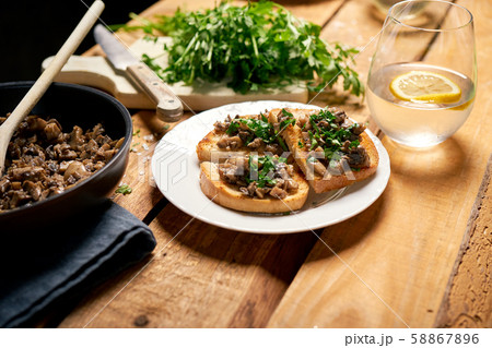 Toasts with mushrooms on white plate on wooden kitchen table Toasts with mushrooms on white plate on wooden kitchen table 58867896