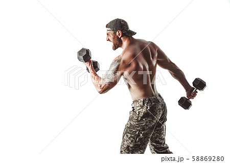 Muscular athlete bodybuilder man in camouflage pants with a naked torso punching with dumbbells like Muscular athlete bodybuilder man in camouflage pants with a naked torso punching with dumbbells like 58869280