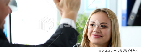 Beautiful blonde clerk giving high five to male customer Beautiful blonde clerk giving high five to male customer 58887447