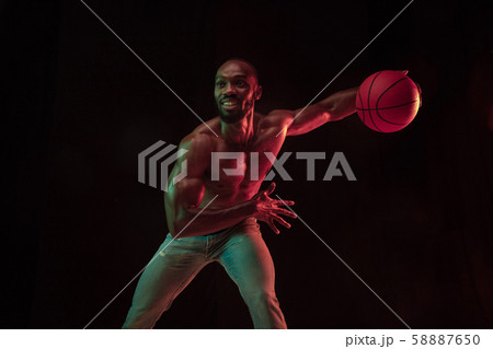 Young african-american basketball player against dark background Young african-american basketball player against dark background 58887650