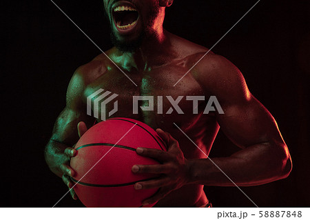 Young african-american basketball player against dark background Young african-american basketball player against dark background 58887848