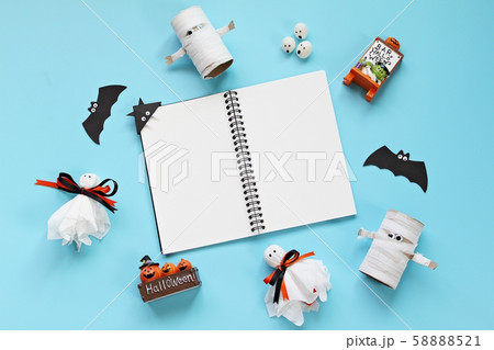 Halloween holiday background concept : Top view or flat lay of notebook paper with Halloween decoration, ghosts and bat on blue background with copy space, ready for adding or mock up 58888521