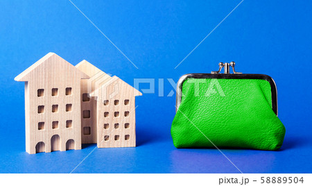 Figures of residential buildings near a large green wallet. concept of the cost of maintaining the building and utility bills. Modernization of housing, improving energy efficiency. Saving to buy home Figures of residential buildings near a large green wallet. concept of the cost of maintaining the building and utility bills. Modernization of housing, improving energy efficiency. Saving to buy home 58889504