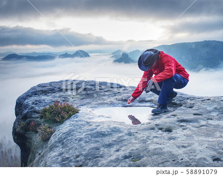 Hiker girl on mountain summit soak leaf in water 58891079
