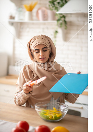 Pretty woman using bright kitchen tools while cooking 58891080