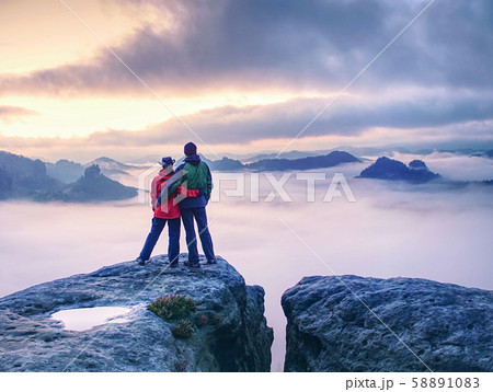 Couple on mountain looking over heavy mist to  Couple on mountain looking over heavy mist to  58891083