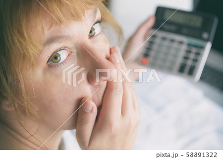 Woman uses a calculator to sum up expenses at home Woman uses a calculator to sum up expenses at home 58891322