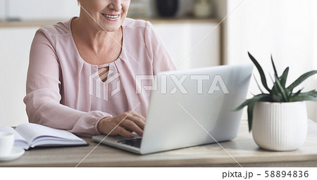 Cropped image of senior business woman working with laptop Cropped image of senior business woman working with laptop 58894836