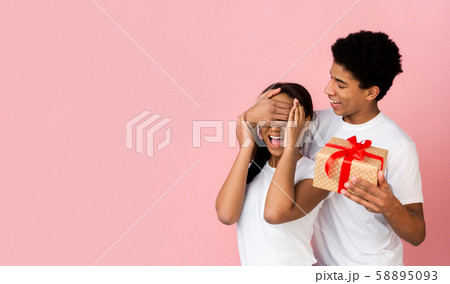 Teen guy preparing gift for girlfriend, closing her eyes Teen guy preparing gift for girlfriend, closing her eyes 58895093
