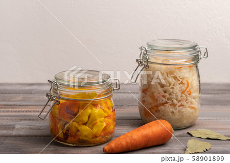 Homemade canned cabbage with carrot in jars with bay leaves on a wooden table. Rustic style 58901899