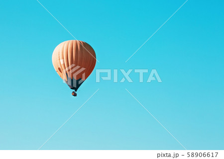 Orange balloon soars against the blue sky 58906617