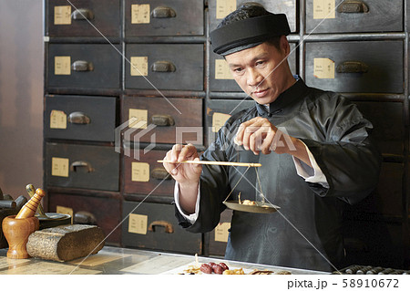 Medicine practitioner weighting herbs and roots 58910672