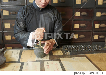 Drugstore worker grinding up ingredients in mortar Drugstore worker grinding up ingredients in mortar 58910681
