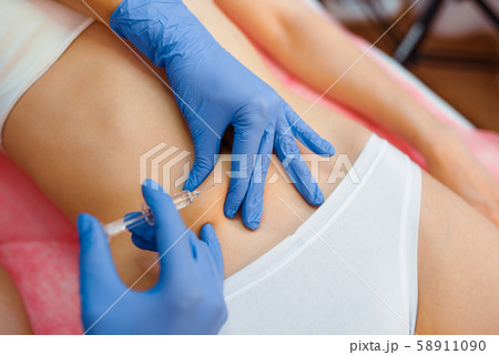 Cosmetician gives botox injection in the stomach Cosmetician gives botox injection in the stomach 58911090
