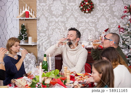 Family gathered around the table for traditional christmas celebration drinking a glass of champagne 58911165