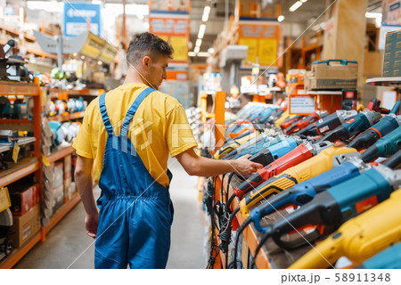 Builder choosing angle grinder in hardware store Builder choosing angle grinder in hardware store 58911348