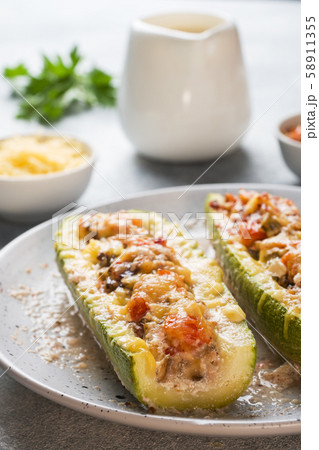 Baked stuffed zucchini boats with minced chicken mushrooms and vegetables with cheese on a plate. Baked stuffed zucchini boats with minced chicken mushrooms and vegetables with cheese on a plate. 58911355