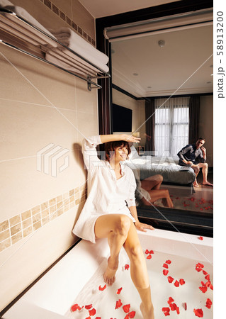 Smiling pretty woman posing in bath with petals Smiling pretty woman posing in bath with petals 58913200
