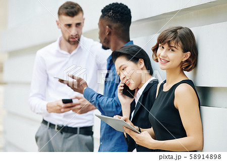 Businesswoman standing outdoors with coworkers Businesswoman standing outdoors with coworkers 58914898