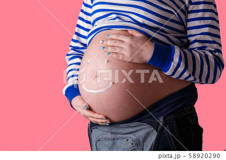 Pregnant woman writing 'smiley' word on her belly. Trendy Pink background. Pregnant woman writing 'smiley' word on her belly. Trendy Pink background. 58920290