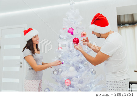 Portrait of joyful couple decorating christmas tree and spending time together during holiday Portrait of joyful couple decorating christmas tree and spending time together during holiday 58921851