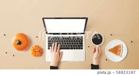 Person using a laptop computer with pumpkins 58923197
