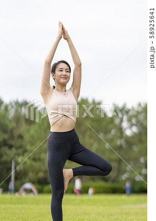 ヨガ 芝生公園でリラックス解放感 木のポーズ 片足立ちでバランス感覚を養い脚やお尻のシェイプアップの写真素材